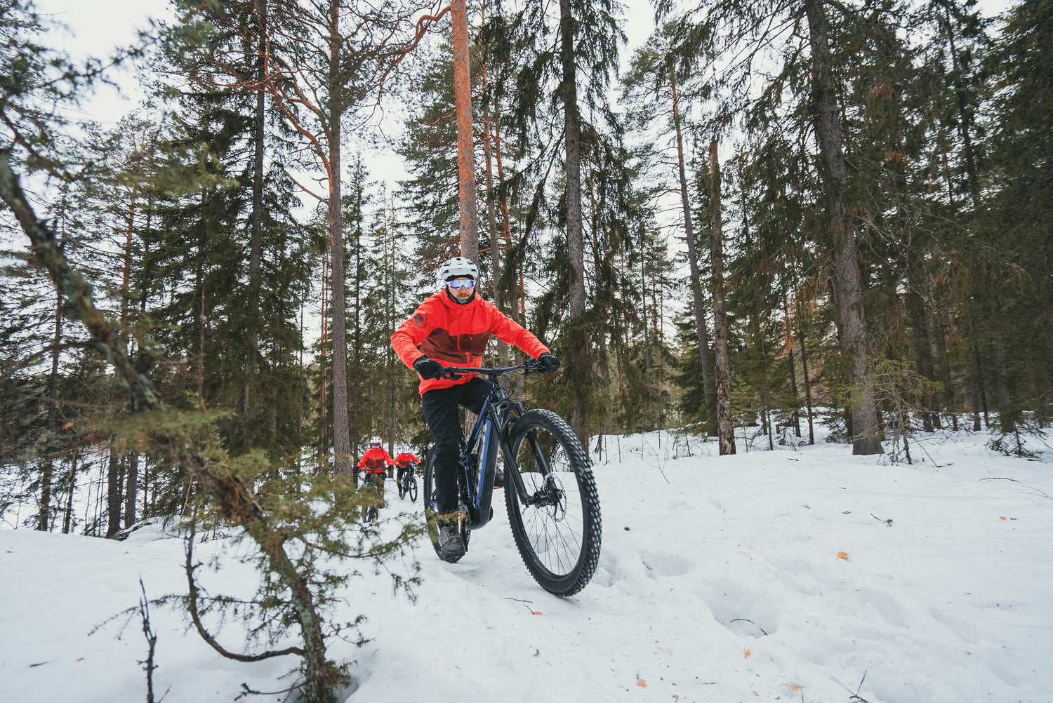 Pyöräilijä ajaa talvikelissä nastarenkailla ja pukeutuneena lämpimiin talvipyöräilyvaatteisiin.